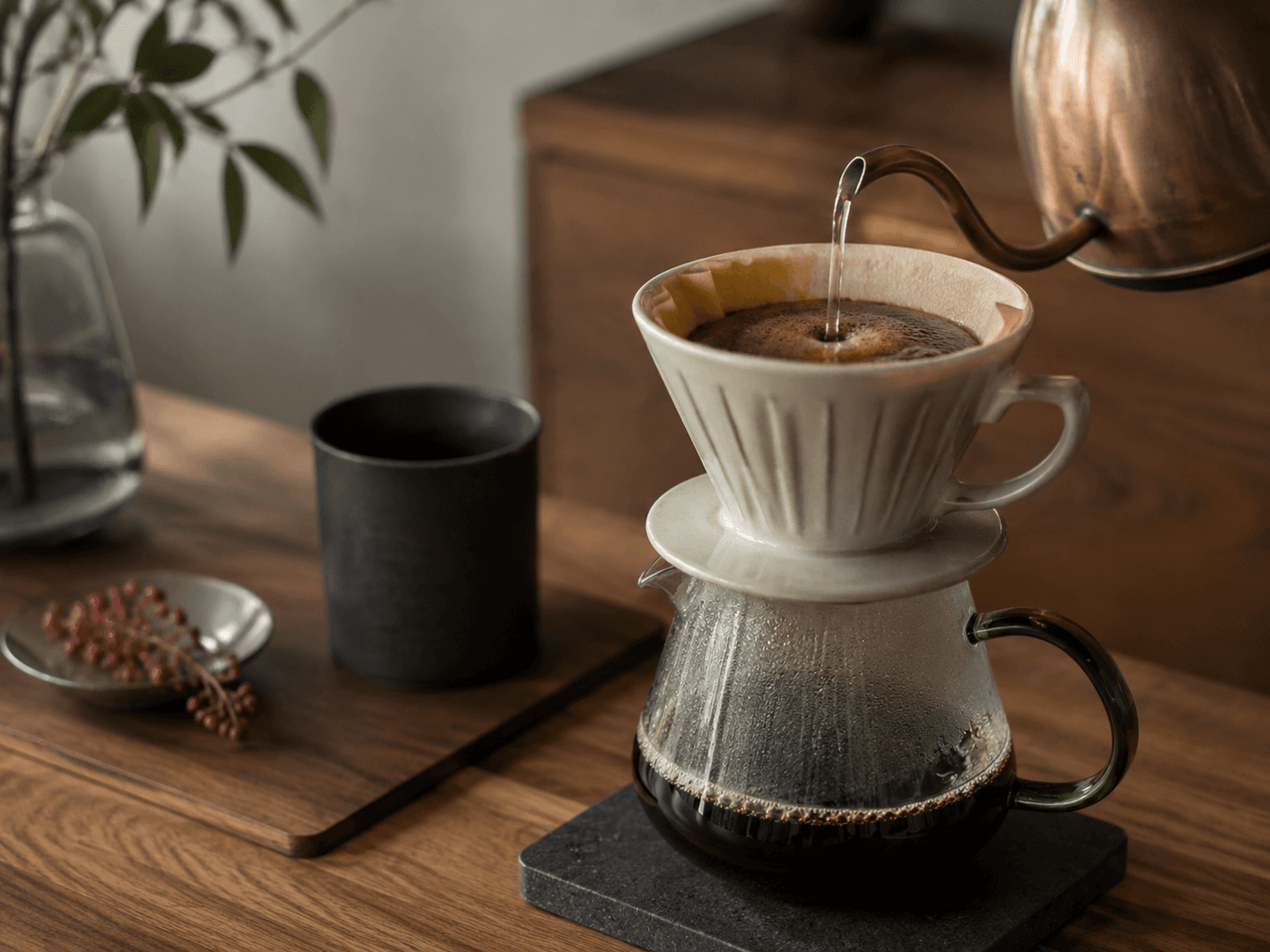 A wooden countertop with a ceramic dripper and glass server